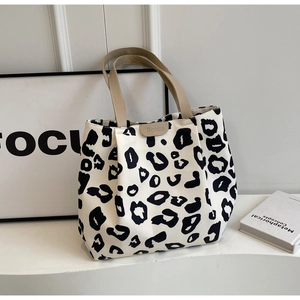 Gros plan du sac cabas en toile léopard avec poignées beiges et étiquette Boons en cuir