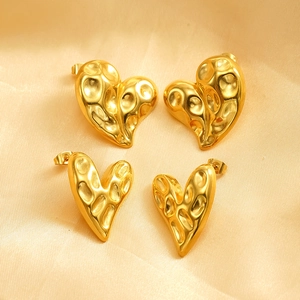 Golden irregular hammered heart-shaped stainless steel stud earrings on silk background