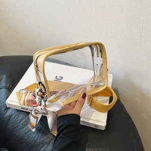 Close-up of transparent PVC crossbody bag with yellow strap and decorative silk scarf