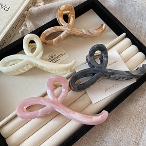 Close-up of four oversized acetate hair claws in cream, amber, and grey marble patterns