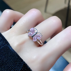Detailansicht eines silbernen Schmetterlingsrings mit vier rosa Steinen am Finger