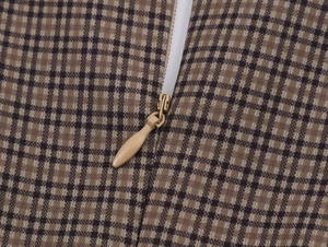 Close-up of the brown plaid fabric texture and invisible zipper detail on the dress