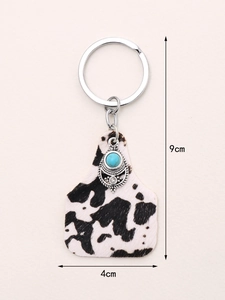 Detail of cow print keychain with turquoise stone and metal ring, 9x4cm dimensions