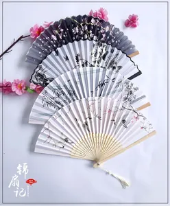 Close-up of Chinese folding fans with floral patterns, bamboo ribs and silk tassels