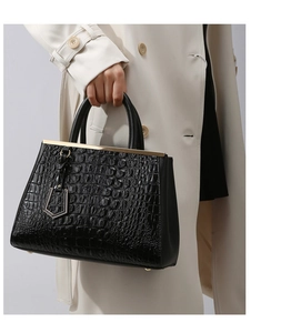 Detail of black crocodile texture tote bag with gold hardware and pentagon charm