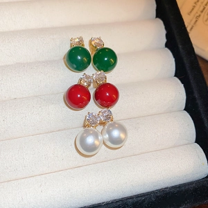 Three pairs of pearl stud earrings with zircon in white, green, and red on a velvet box