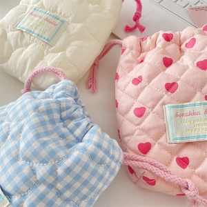 Close-up of quilted drawstring bags in heart and plaid patterns for camera storage