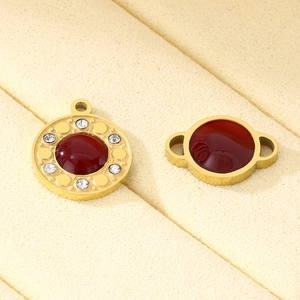 Macro view of gold stainless steel pendants with deep red gemstones and pavé accents