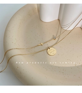 Detail of 18K gold-plated double-layer necklace with cross and engraved coin pendant