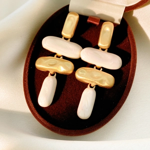 Detailansicht goldener mattierter geometrischer Ohrringe mit weißem Marmorharz im Etui