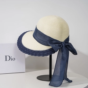 Women's woven straw sun hat with wide navy wavy brim and large trailing ribbon bow