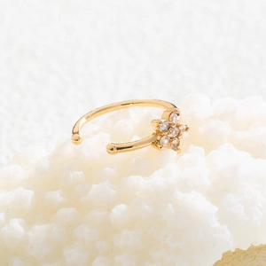 Macro shot of a golden star flower nose stud featuring clear sparkling crystals