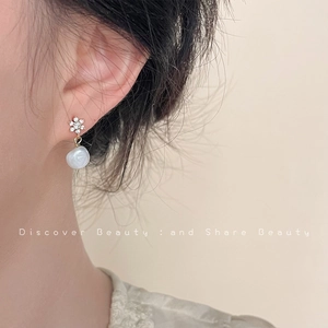 Close-up of baroque pearl earring with a zircon snowflake stud on a model's ear
