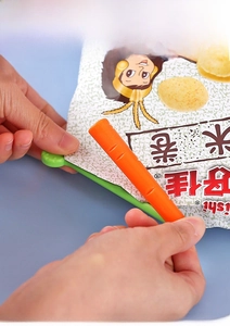 Gros plan d'une main utilisant des clips carotte pour fermer un sac alimentaire