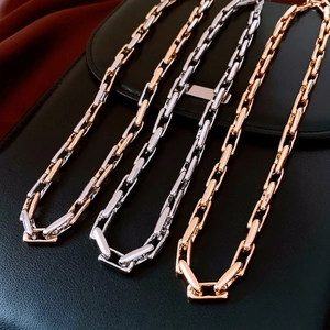 Detailed view of chunky metal link necklaces in silver and rose gold on black leather