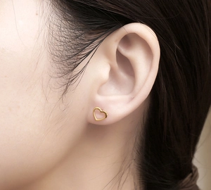 Close-up of heart-shaped hollow earrings in gold finish worn by a model