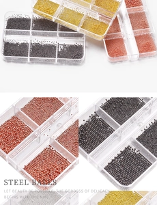 Macro shot of assorted steel micro balls for nail art in gold, black and rose gold boxes