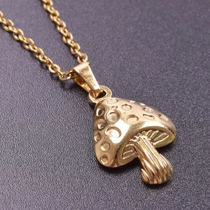 Close-up of polished gold mushroom pendant necklace on a dark textured background