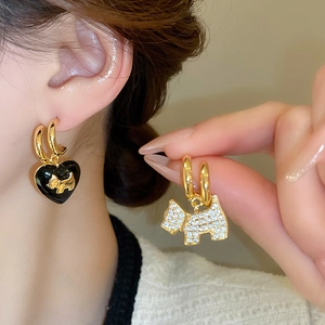 Macro shot of asymmetrical gold plated puppy and black heart stud earrings with zircons