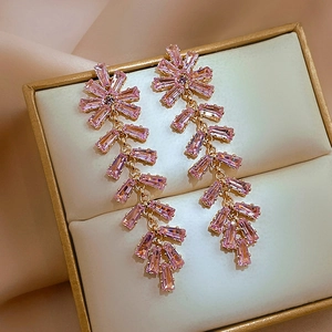 Close-up of pink zircon wheat ear tassel earrings on a velvet jewelry box cushion