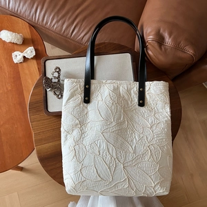 Close-up of retro canvas tote bag with leaf embroidery and black leather strap details