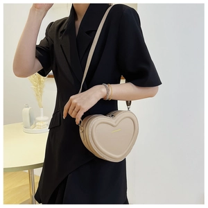 Dettaglio della borsa a tracolla crema a forma di cuore con scritta Fashion & Bag indossata da modella