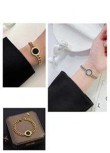 Close-up of thick chain bracelets with Roman numeral round pendants in gold and silver