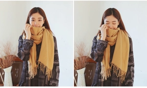 Detail of ginger yellow cashmere-feel scarf featuring delicate tassel edges and soft texture
