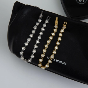 Close-up of heart-shaped zircon tennis bracelets in gold and silver finish with fold-over clasp