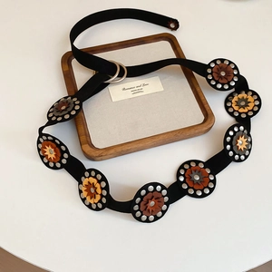 Close-up of bohemian leather flower patches with silver rivets on a black waist belt