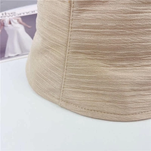 Gros plan sur la texture du tissu plissé beige et les coutures soignées de ce bob