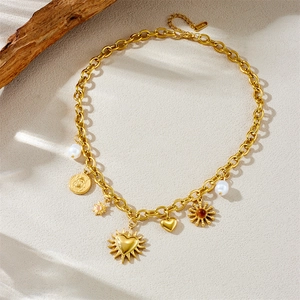 Golden chunky chain necklace with heart, sun, pearl and beetle charms on a textured base