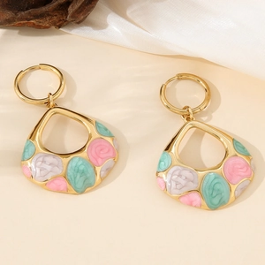 Golden teardrop earrings with pink floral enamel inlay on elegant silk background