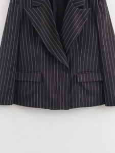 Detail of a black striped blazer featuring a peak lapel and single button closure