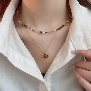 Détail d'un collier doré à deux rangs avec perles brunes et pendentif sur modèle