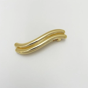 Close-up of golden irregular wavy alloy hair clip with smooth metallic finish