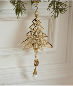 Golden hollow Christmas tree metal ornament with crystal drops hanging on a pine branch