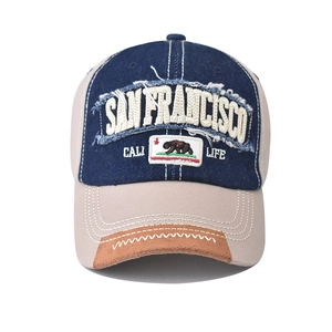 Close-up of embroidered San Francisco logo and bear patch on washed denim baseball cap