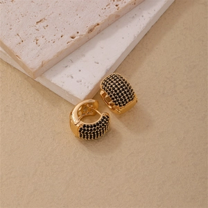 Boucles d'oreilles créoles larges dorées serties de zircons noirs sur fond marron mat