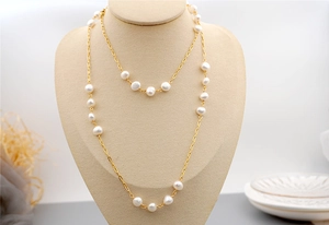 Close-up of long necklace with baroque pearls and gold chain on jewelry mannequin