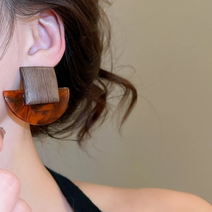 Close-up of geometric wood and amber resin stud earrings worn on model for a retro look