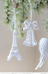 White Christmas ornaments with Eiffel Tower and angel wings hanging on a pine branch