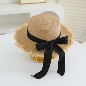 Detail of raffia straw hat with frayed edges and elegant black ribbon bow accessory