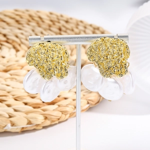 Bohemian shell pearl drop earrings with textured gold metal displayed on a T-bar stand