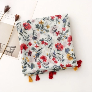 Detail shot of white cotton scarf with red floral print and colorful tassel trim fringe