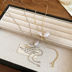 Close-up of butterfly pendant with baroque pearls and diamonds on a gold snake chain