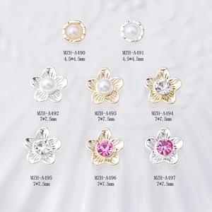 Flat lay of alloy nail art charms featuring pearl flowers and rhinestones in gold and silver