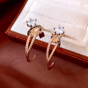 Macro shot of two-tone C-shape earrings with twisted metal and sparkling zircon stones