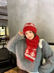 Dettaglio del set cappello e sciarpa in maglia rossa con motivi a fiocco di neve