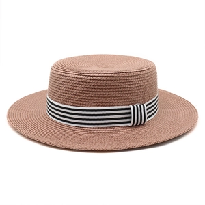 Close-up of a woven straw boater hat featuring a stylish black and white striped ribbon